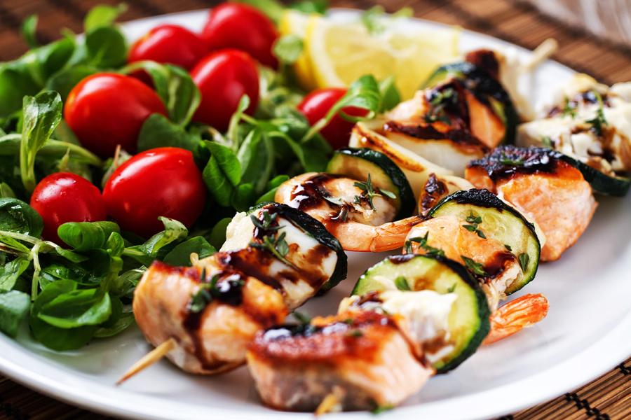 Brochetas de rape, salmón y langostinos acompañadas de ensalada.
