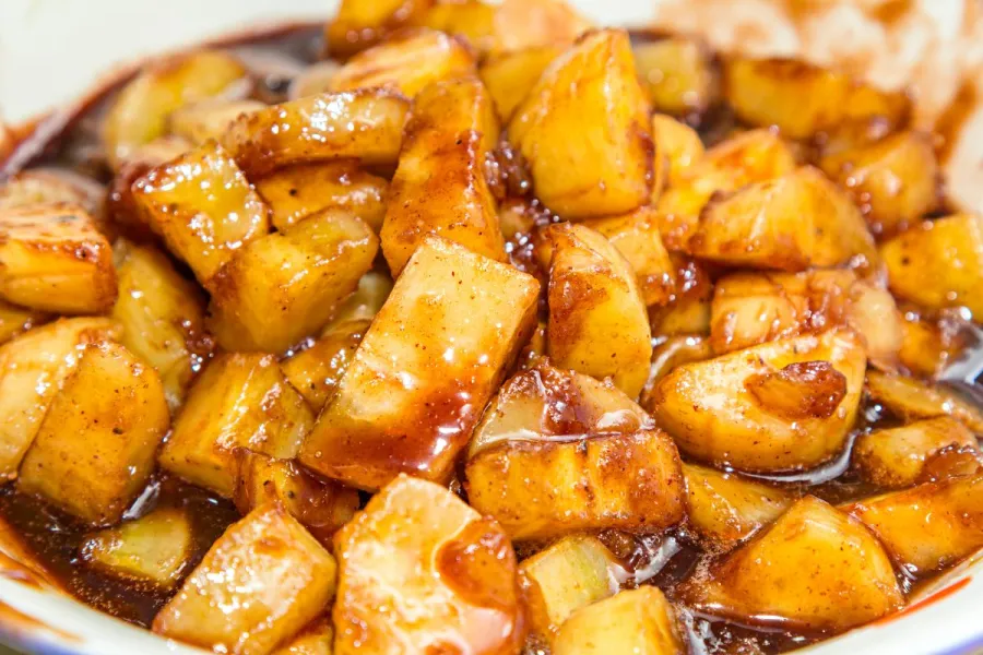 Detalle de plátano caramelizado, cortado en trozos pequeños para servir como acompañamiento.