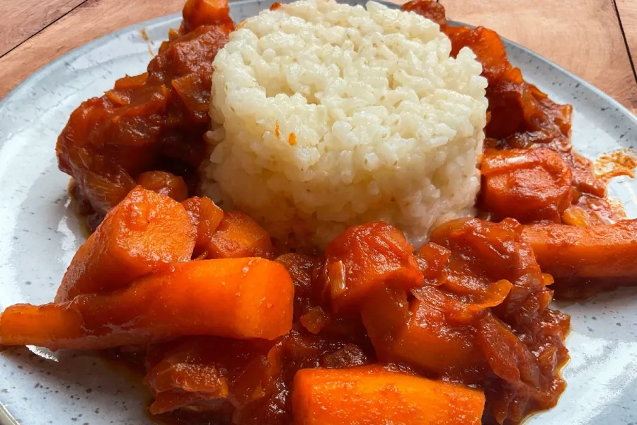Un plato de zanahorias guisadas servidas con un molde de arroz blanco.