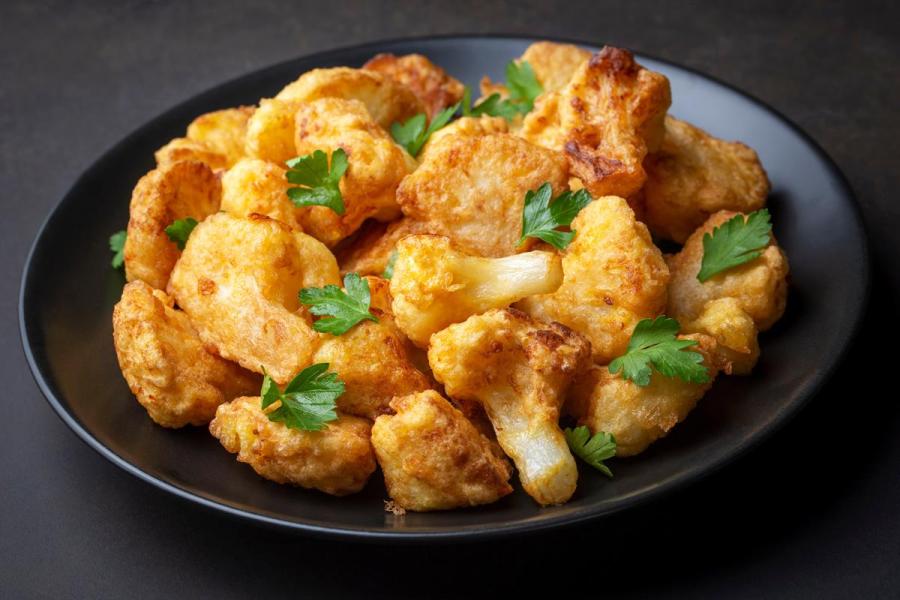 Un plato de coliflor rebozada decorada con perejil.