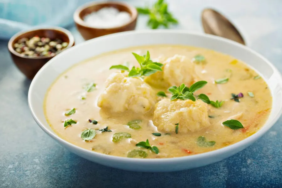 Un plato de sopa de pollo con bolas de masa.