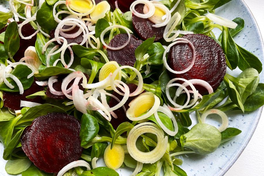 Un plato con ensalada de remolacha y puerro.