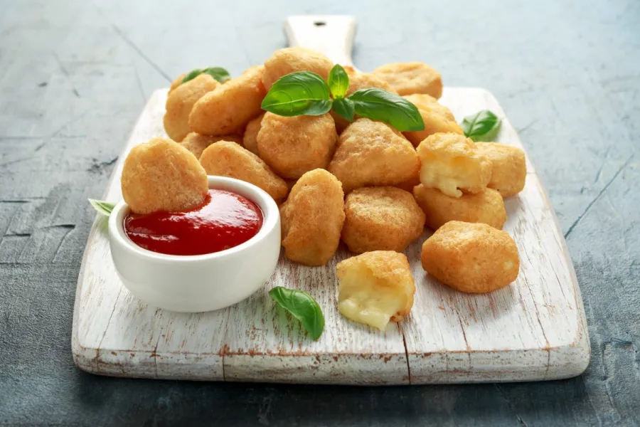 Bolitas de mozzarella rebozadas y fritas servidas con kétchup.