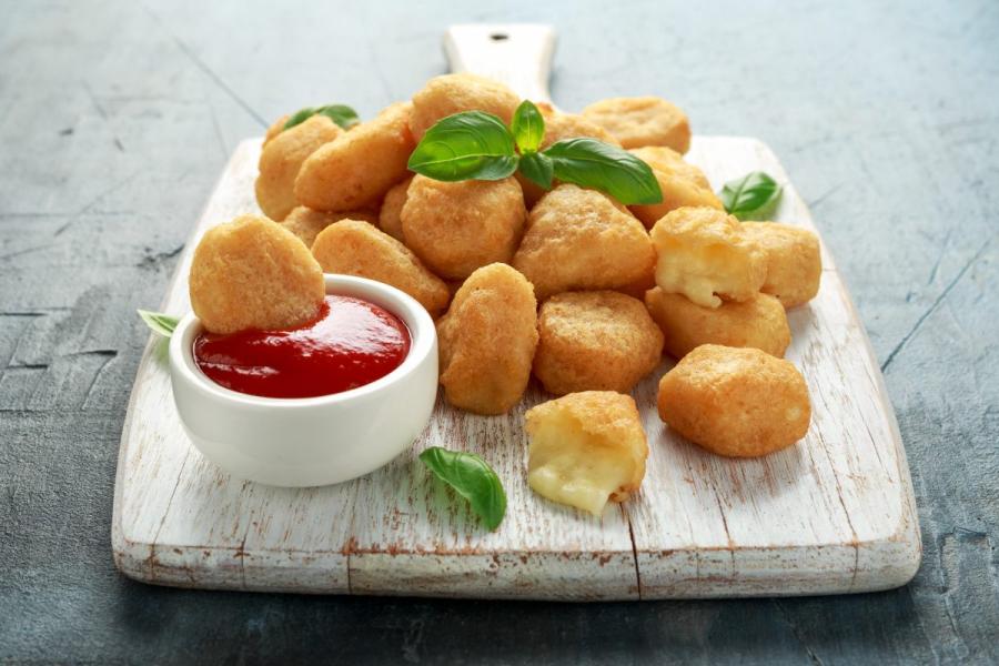 Bolitas de mozzarella rebozadas y fritas servidas con kétchup.