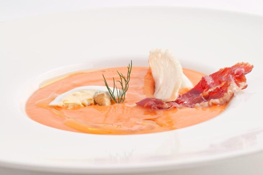 Un plato de salmorejo cordobés servido con huevo duro, pescado y jamón serrano.