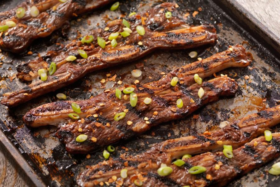 Costillas adobadas y cocinadas sobre la barbacoa al estilo coreano sobre una tabla de madera.