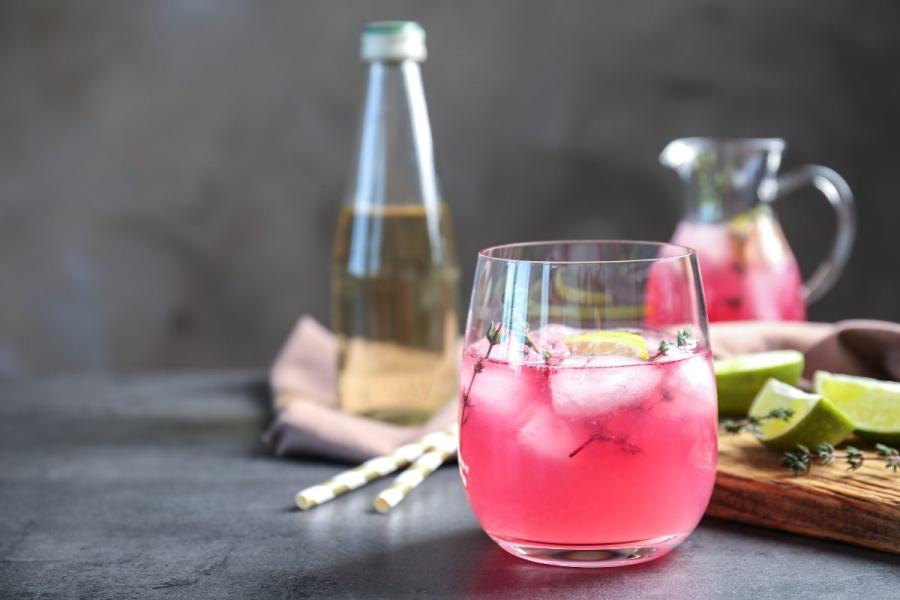 Una copa y una jarra de unspritzer de vino y zumo de fruta servido con hielo.