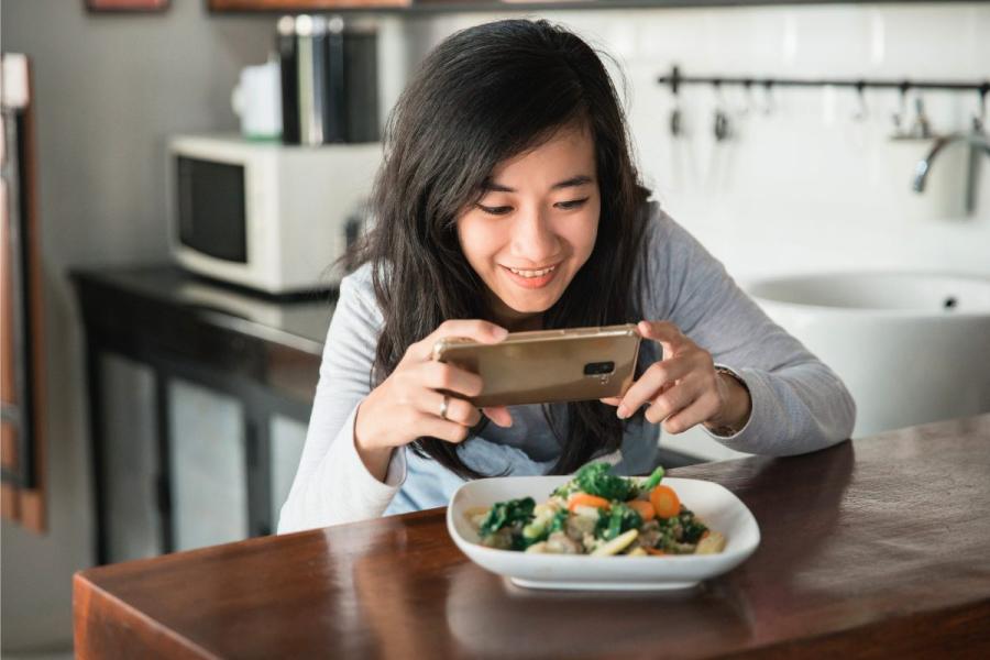 Una mujer sacando una fotografía del plato que ha preparado con su teléfono móvil.
