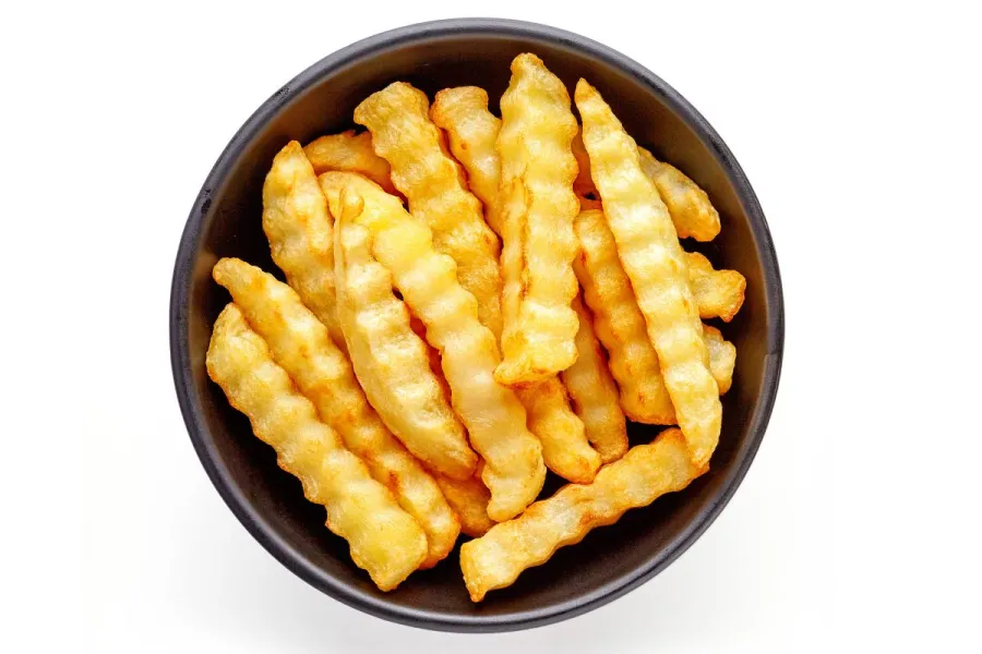 Un cuenco con patatas fritas cortadas en forma de varitas onduladas.