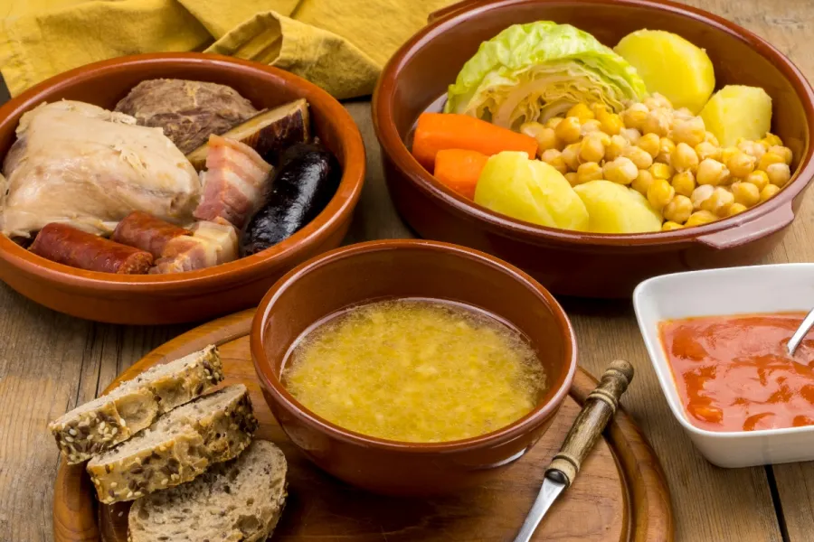 Un cocido madrileño completo. con su sopa, verduras, garbanzos y carnes.