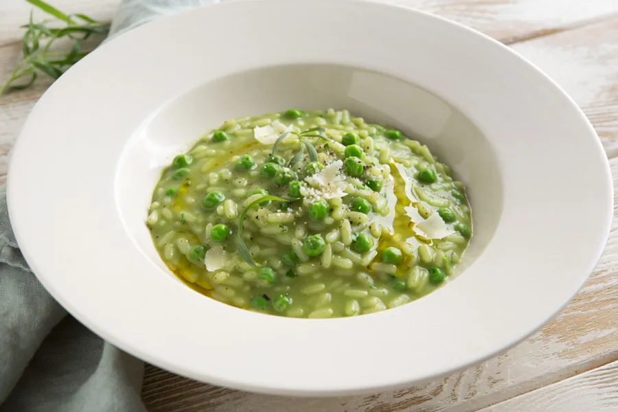 Risotto de guisantes y estragón servido en plato hondo.