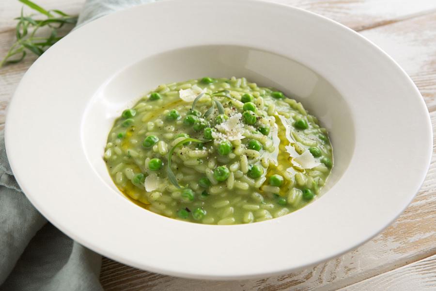 Risotto de guisantes y estragón servido en plato hondo.