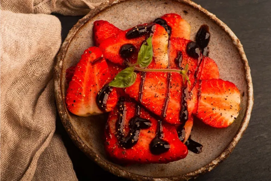 Fresas con pimienta y vinagre balsámico en un cuenco de cerámica artesanal.