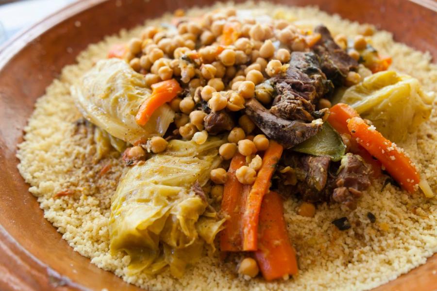 Cuscús tradicional con garbanzos, zanahorias, repollo y carne guisada servido en fuente de barro.