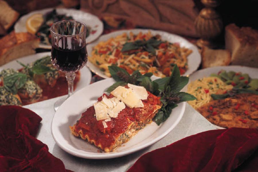 Comida italiana en la mesa con copas de vino tinto.