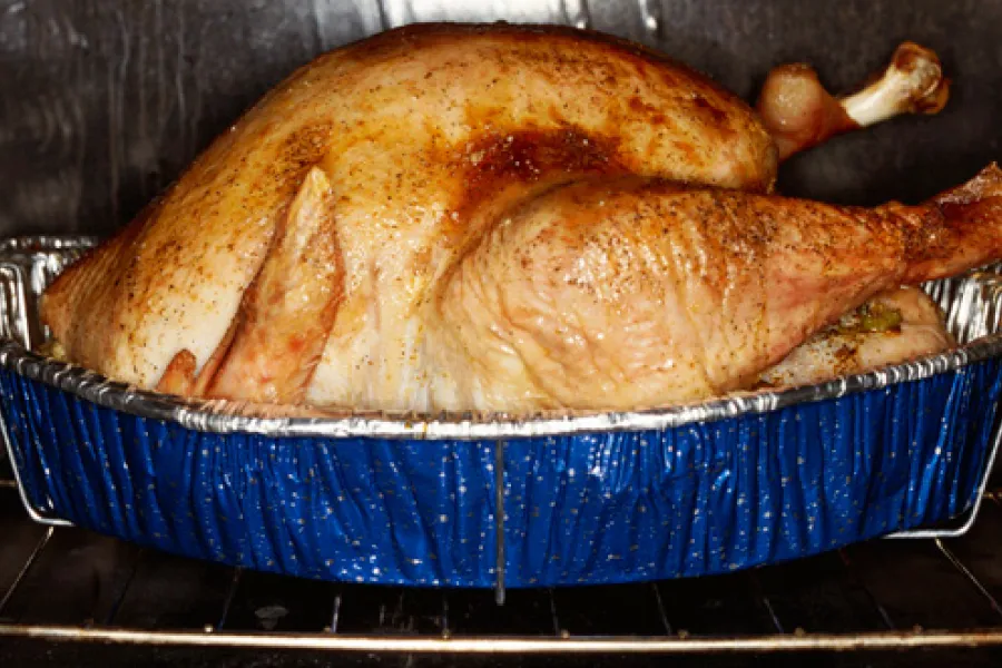 Un pavo asado en una fuente dentro del horno.