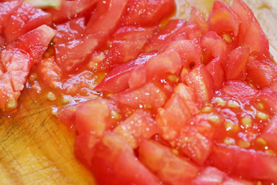 Tomate picado sobre una tabla de cortar de madera.