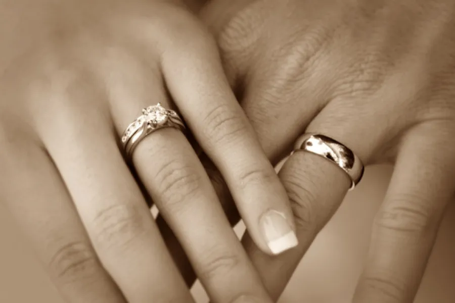 Dos manos cogidas llevando anillos de matrimonio.