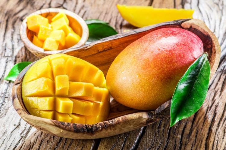 Un mango entero y medio mango cortado en una cesta.