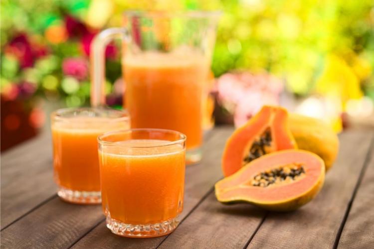 Una jarra y dos vasos con zumo de papaya.