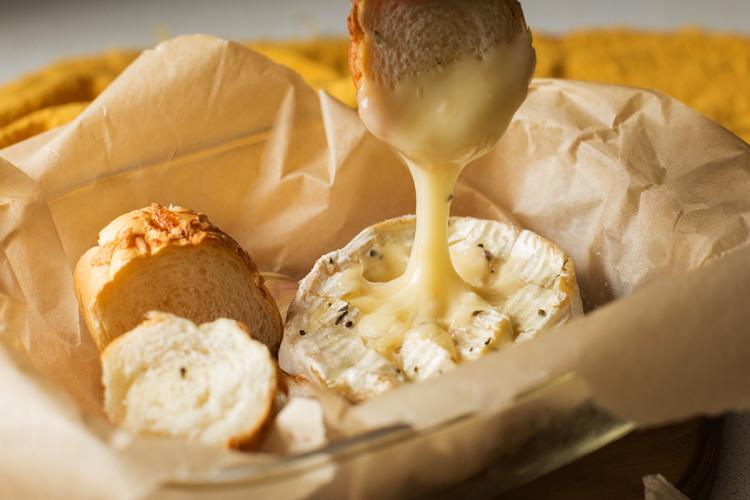 Un trozo de pan mojado en queso fundido en el horno , queso fundido y otras rebanadas de pan.