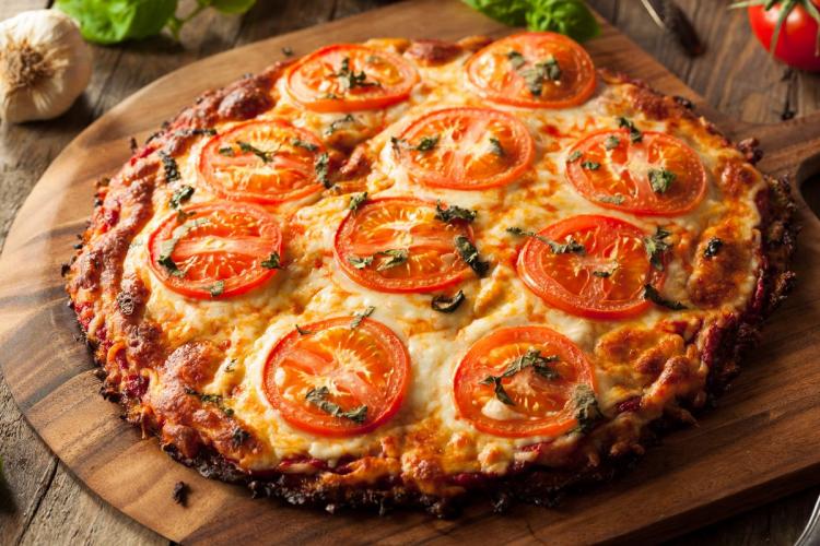 Pizza de queso y rodajas de tomate con base de coliflor.
