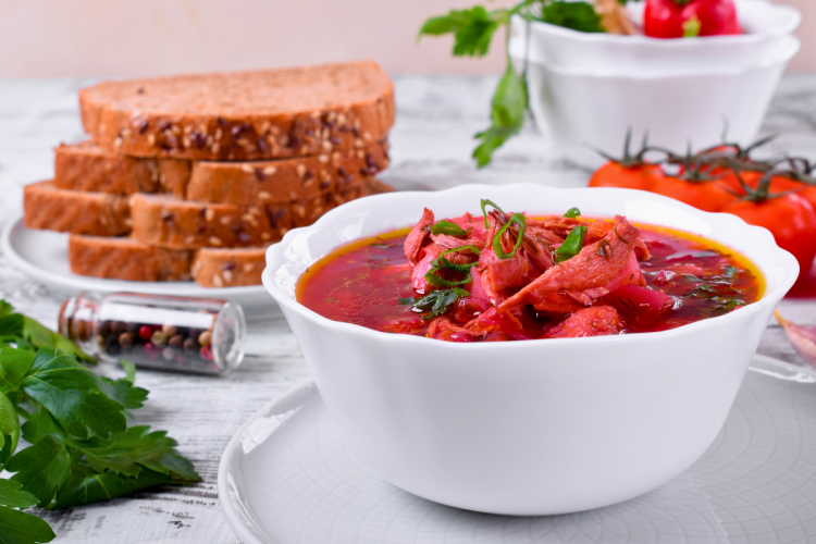 Sopa borscht con carne servida en un cuenco blanco.