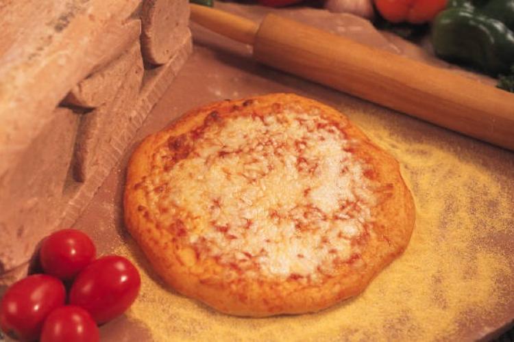 Una pizza tradicional tomates y un rodillo.